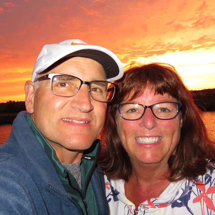 Richard Zimman ’73 & Valerie Cox smiling in front of a sunset.